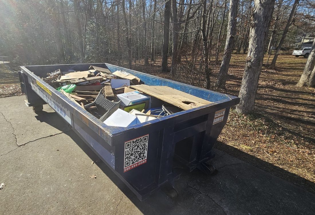 Integrity Roll Off dumpster loaded with household junk in a driveway