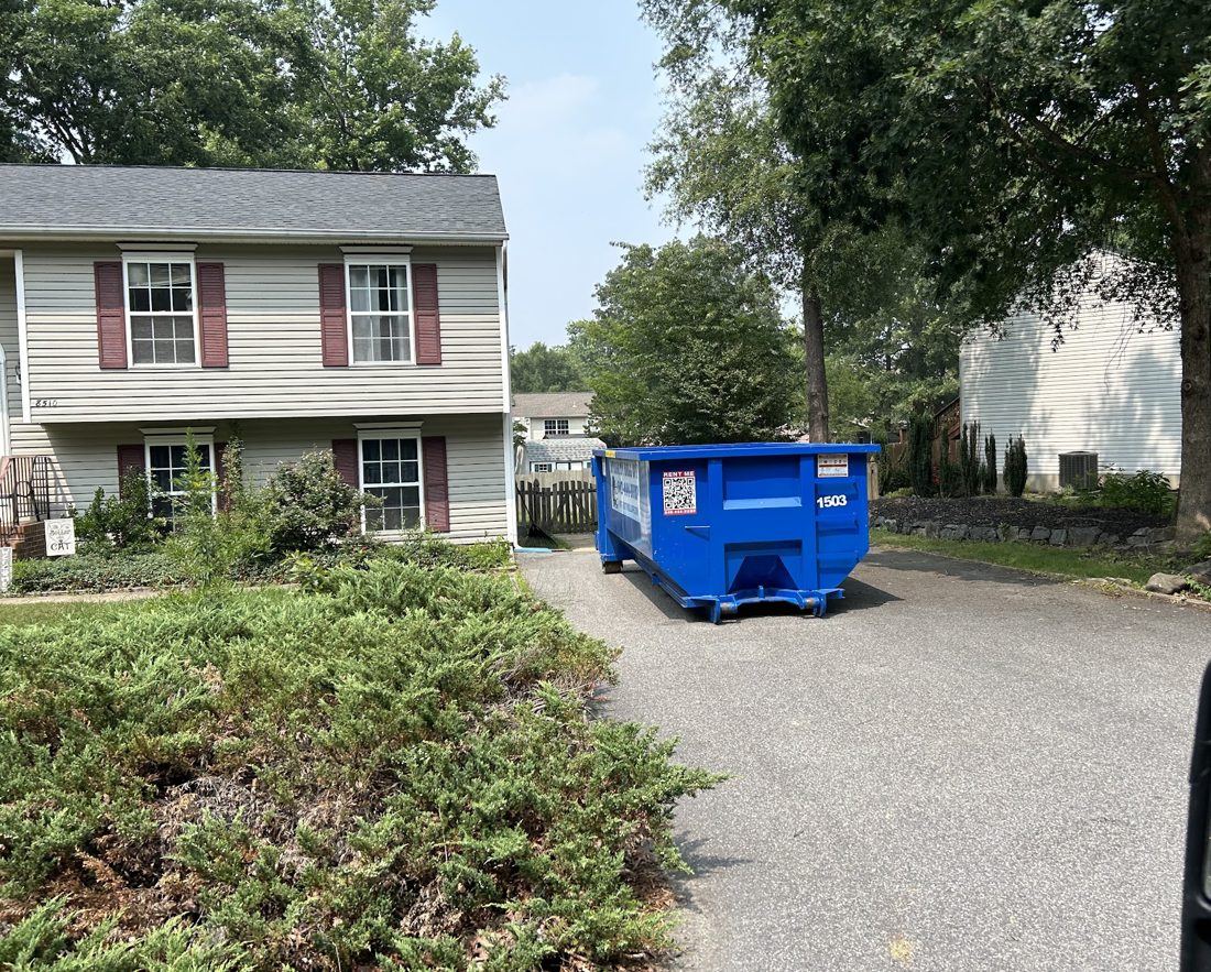 Integrity Roll Off 15 yard dumpster set in a driveway between two houses