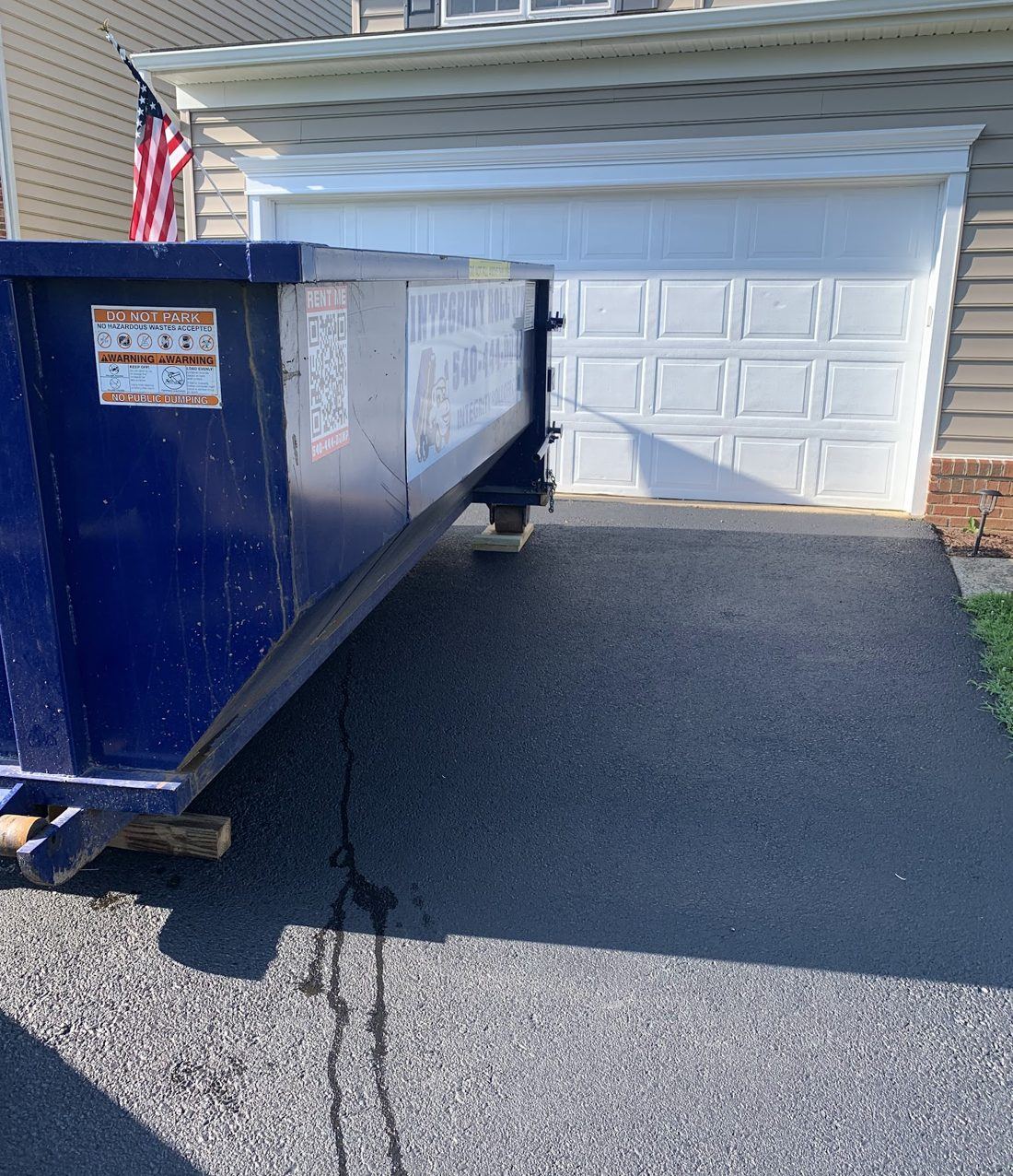 20 yard Integrity Roll Off dumpster set on boards beside a garage